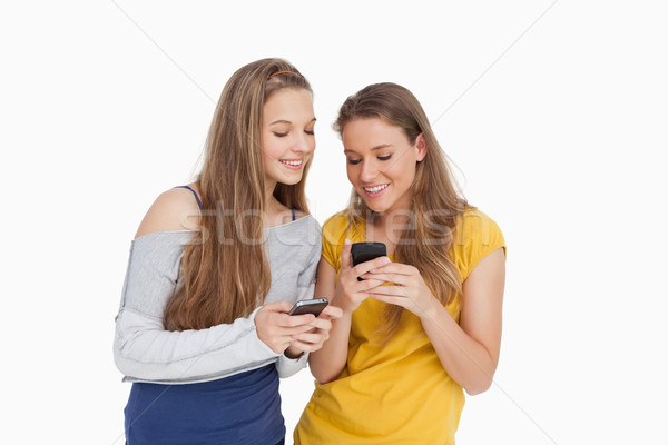 Deux jeunes femmes souriant regarder blanche lecture [[stock_photo]] © wavebreak_media