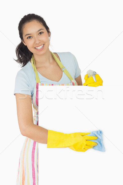 Cheerful woman wiping down white surface in apron and rubber gloves Stock photo © wavebreak_media
