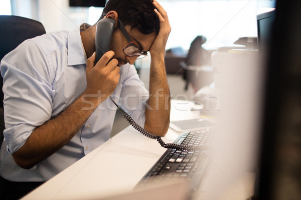 Tensed businessman talking on land line in office Stock photo © wavebreak_media