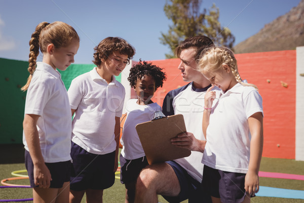 Coach and schoolkids discussing on clipboard Stock photo © wavebreak_media
