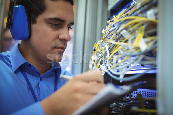 Technician maintaining record of rack mounted server on clipboard Stock photo © wavebreak_media