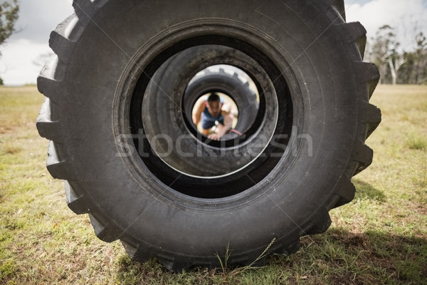 Man crawling through the tire during obstacle course Stock photo © wavebreak_media