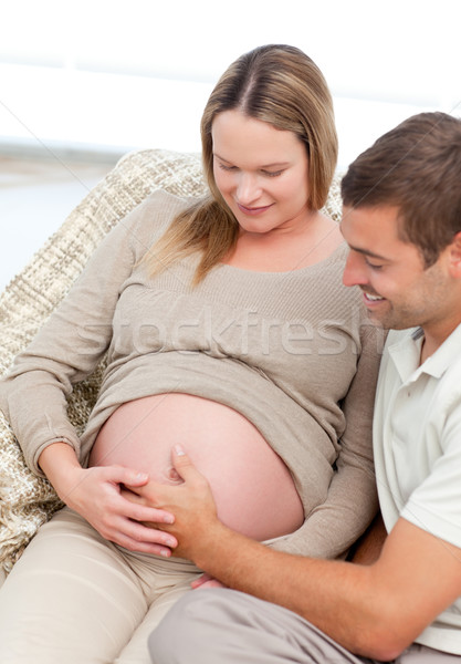 Beautiful future parents feeling their unborn child sitting in the sofa at home Stock photo © wavebreak_media