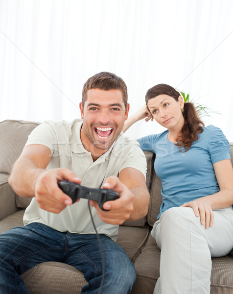 Bored woman looking at her boyfriend playing video game on the sofa Stock photo © wavebreak_media