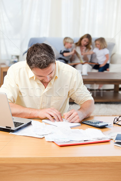 Man calculating his bills while his family are on the sofa Stock photo © wavebreak_media