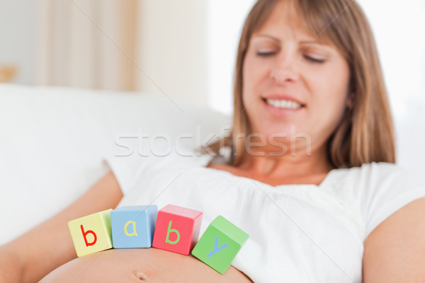 Gorgeous pregnant woman playing with wooden blocks while lying on a sofa in her living room Stock photo © wavebreak_media