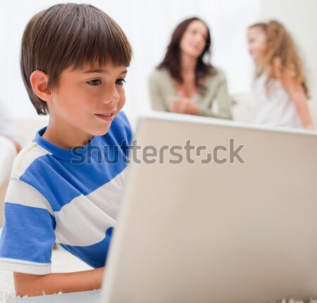 Stock photo: Young boy playing computer games with his family behind him