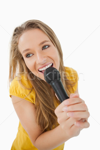 Fisheye view of blonde girl singing with a microphone against white background Stock photo © wavebreak_media