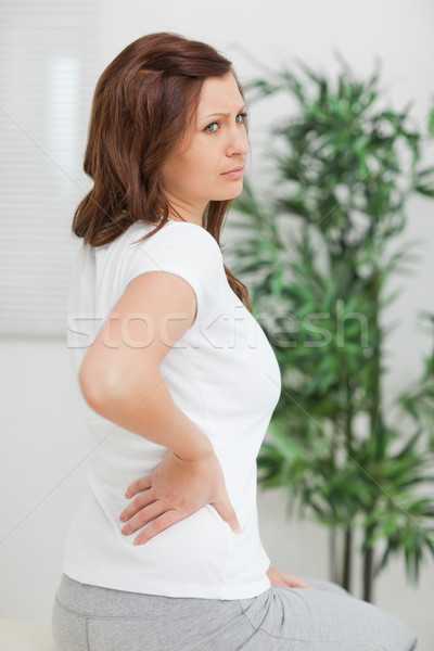 Woman touching her back while looking away in a room Stock photo © wavebreak_media