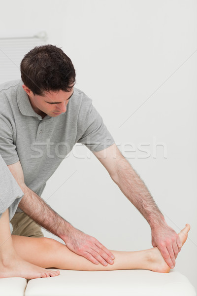 Serious physiotherapist working on the calf of a patient in a room Stock photo © wavebreak_media