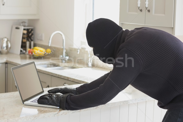 Rapinatore utilizzando il computer portatile cucina sconosciuto home computer Foto d'archivio © wavebreak_media