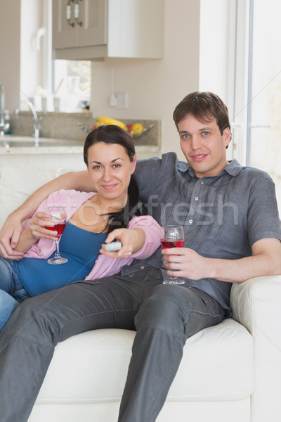 Stock photo: Young couple sitting on the couch while watching television and drinking wine