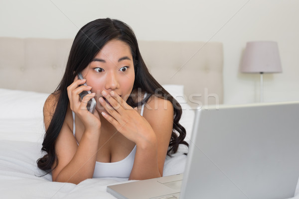 Shocked woman looking at laptop on the phone Stock photo © wavebreak_media