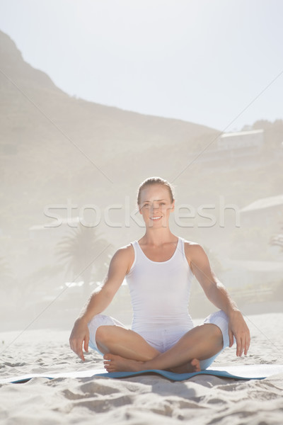 Smiling woman sitting in lotus pose on beach Stock photo © wavebreak_media