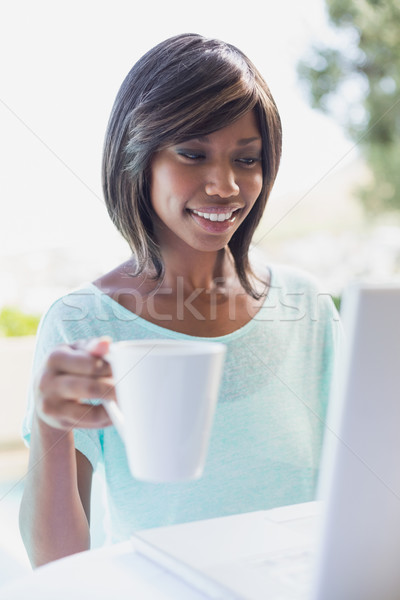 Stock photo: Pretty woman sitting outside using laptop having coffee