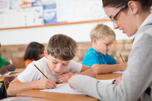 Stock photo: Cute pupils writing at desk in classroom