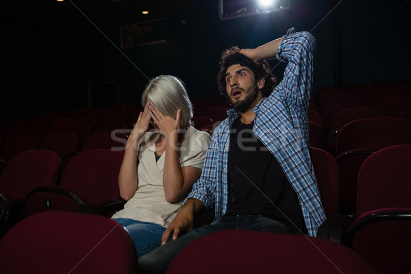 Stock photo: Couple with shocked expression looking at the movie in theatre