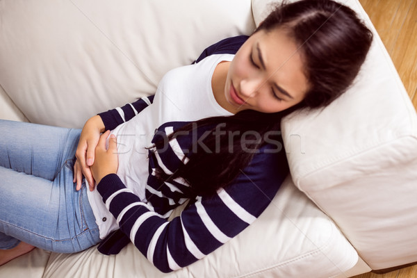 Asian woman lying on the couch with cramps Stock photo © wavebreak_media