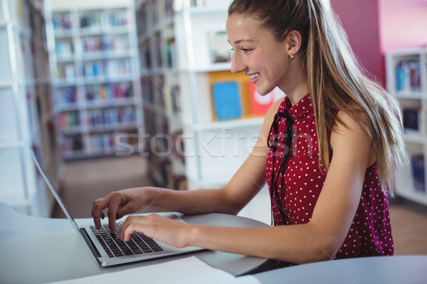 Foto stock: Feliz · colegiala · usando · la · computadora · portátil · biblioteca · escuela · ordenador