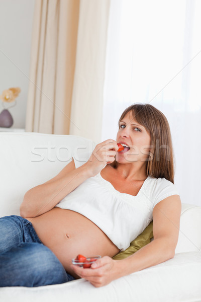 Goed kijken zwangere vrouw eten aardbeien sofa glimlach Stockfoto © wavebreak_media