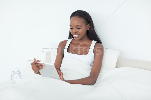 Stock photo: Woman using a tablet computer in her bedroom