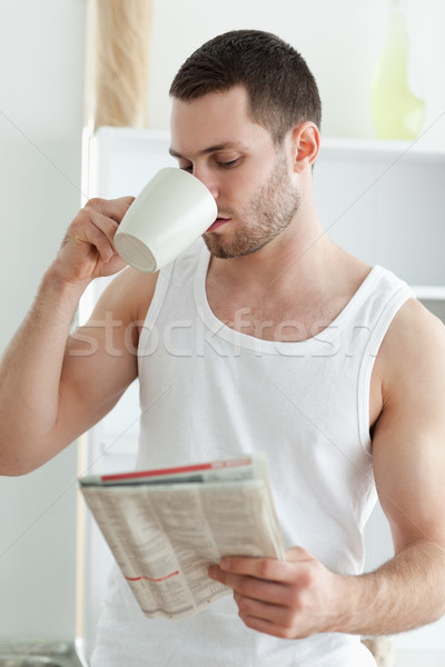 Portrait of a young man drinking tea while reading the news in his kitchen Stock photo © wavebreak_media