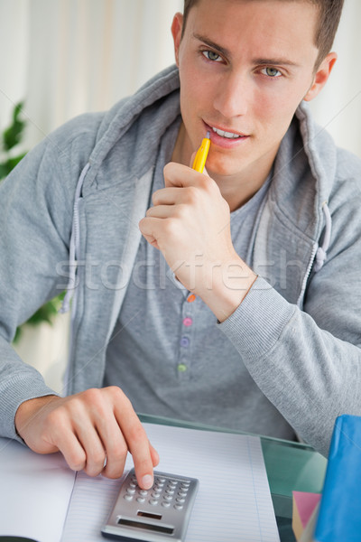 Handsome student using a calculator while doing his homework Stock photo © wavebreak_media