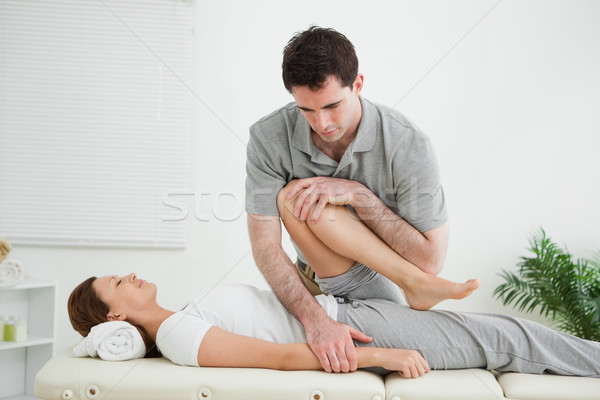 Stock photo: Brown-haired woman being stretched by a man in a room