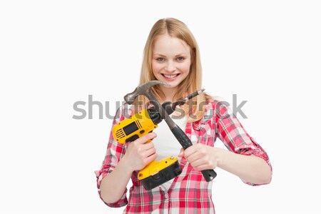 Woman holding an electric screwdriver and a hammer against white background Stock photo © wavebreak_media