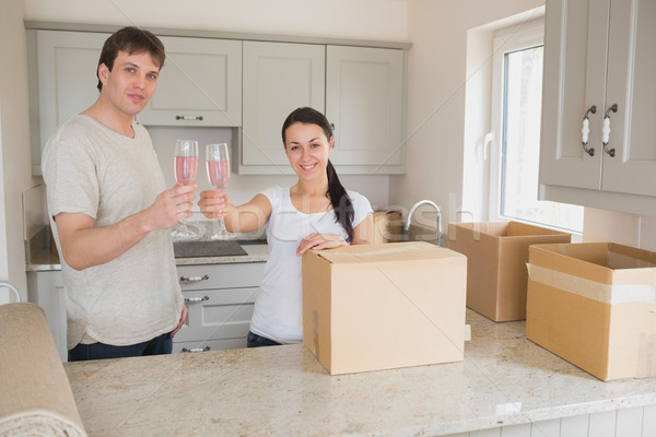 Stock photo: Young couple celebrating their move in the kitchen while drinking
