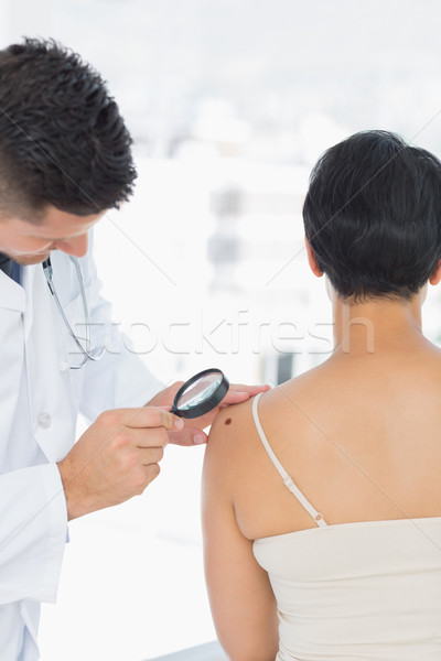 Dermatólogo examinar topo mujer lupa clínica Foto stock © wavebreak_media