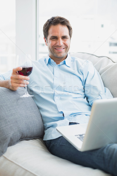 Przystojny mężczyzna relaks sofa szkła wino czerwone za pomocą laptopa Zdjęcia stock © wavebreak_media