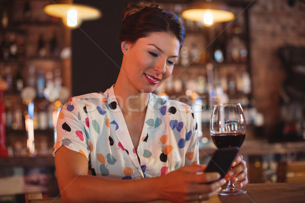 Young woman using mobile phone while having wine Stock photo © wavebreak_media