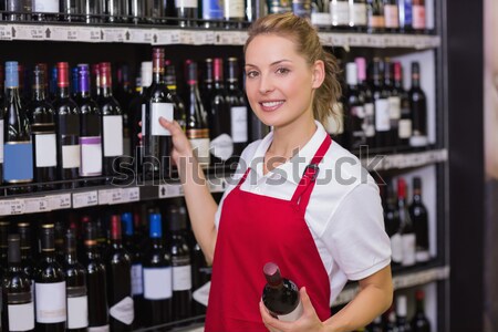 Stock photo: Smiling woman picking bottle of wine