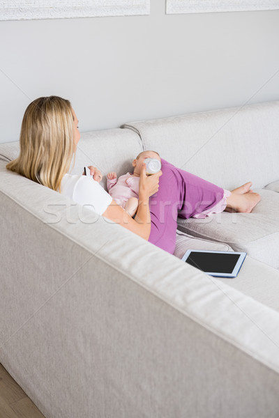 Mother feeding baby with milk bottle in living room Stock photo © wavebreak_media