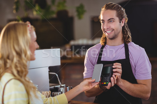 Woman paying bill through smartphone using NFC technology Stock photo © wavebreak_media