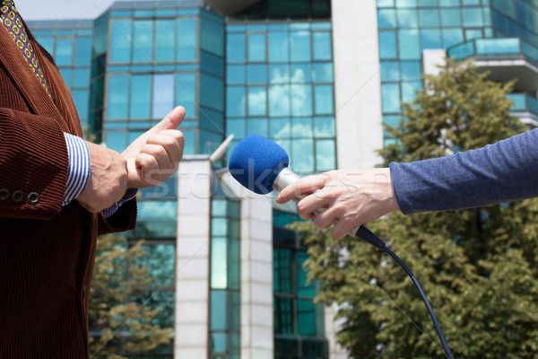 Reporter interviewing businessman, corporate building in background Stock photo © wellphoto