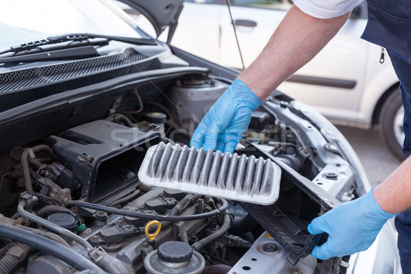 Stock photo: Auto mechanic wearing protective work gloves holds a dirty air f