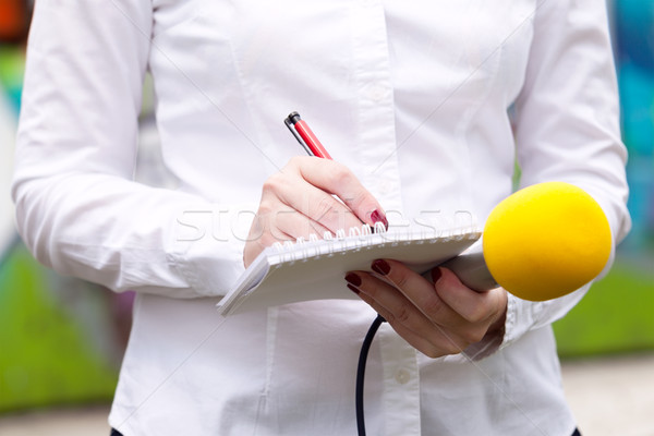 Female journalist at news conference, writing notes, holding mic Stock photo © wellphoto