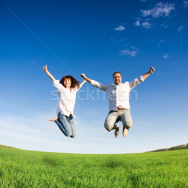 Fericit cuplu jumping verde câmp Blue Sky Imagine de stoc © Yaruta