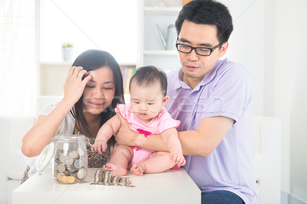Asian baby putting coins into the glass bottle with help of pare Stock photo © yuliang11