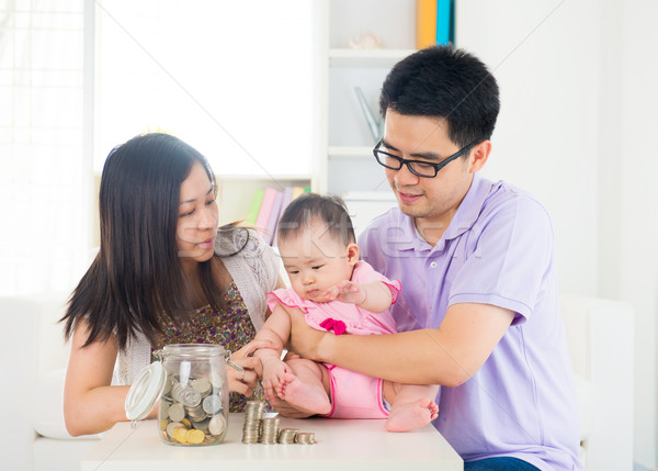 Asian baby putting coins into the glass bottle with help of pare Stock photo © yuliang11
