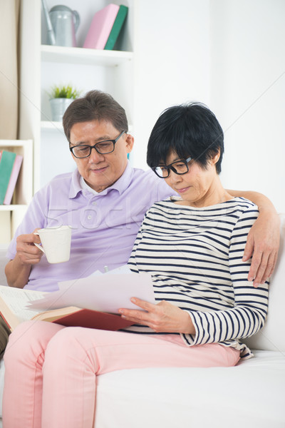 senior asian couple reading a book together at home. Stock photo © yuliang11