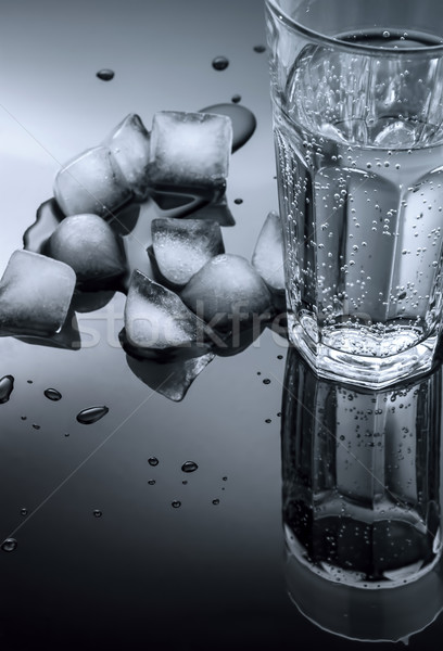 Stock photo: glass of water and ice cubes on a dark background