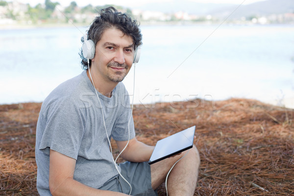 Hombre tableta joven auriculares playa Foto stock © zittto