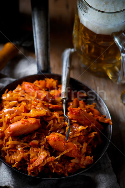 stewed cabbage with sausages in a vintage frying pan and a mug with beer. Stock photo © zoryanchik