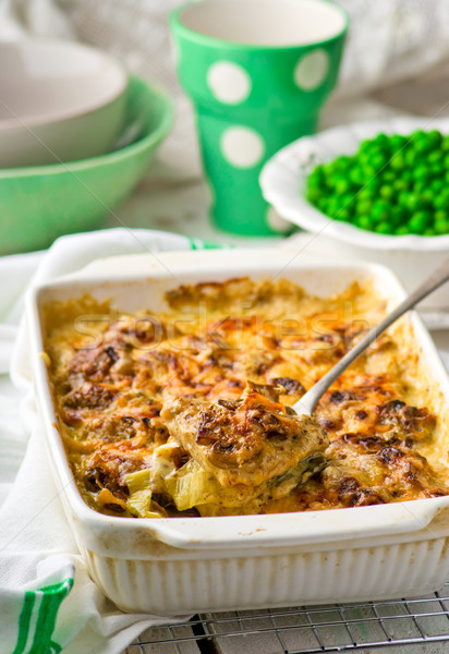 baked pudding with fish and mushrooms in a ceramic form for roasting and green peas in a bowl. Stock photo © zoryanchik