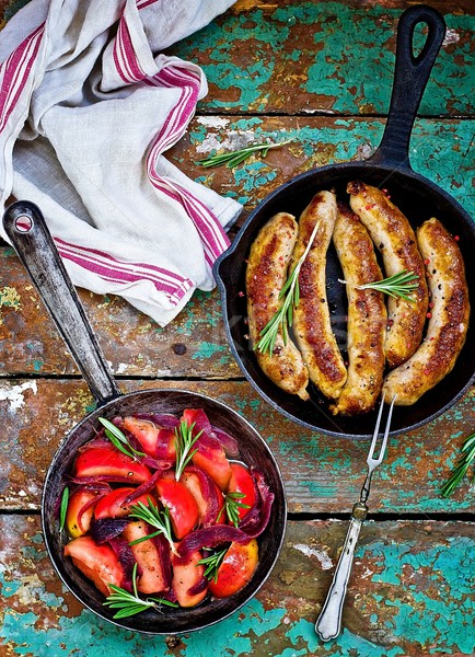 fried sausages with apples, onions and rosemary in a frying pan  Stock photo © zoryanchik