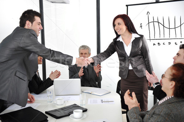 Business partners shaking hands after making deal while their co-workers applauding Stock photo © zurijeta