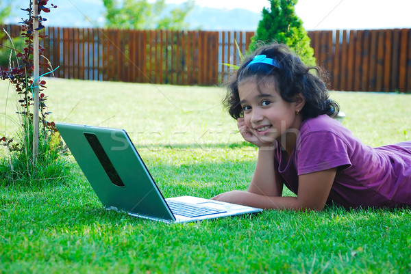A little cute girl laying down in grass with laptop Stock photo © zurijeta